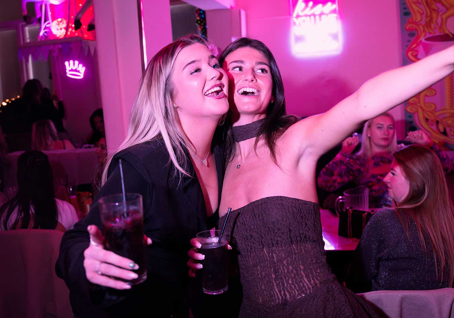 Saturday night clubbing vibes with girls having fun in pink restaurant close up