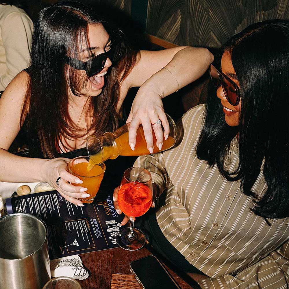 Two women drinking bottomless cocktails with PizzaExpress, The Pheasantry a a bottomless brunch on King's Road with Lovebrunch